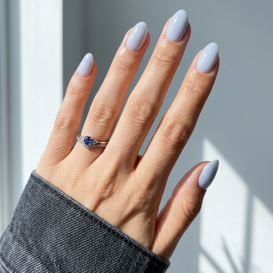 Hand with light blue nail polish wearing a ring on a neutral background
