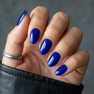 Hand with blue nail polish on a gray background
