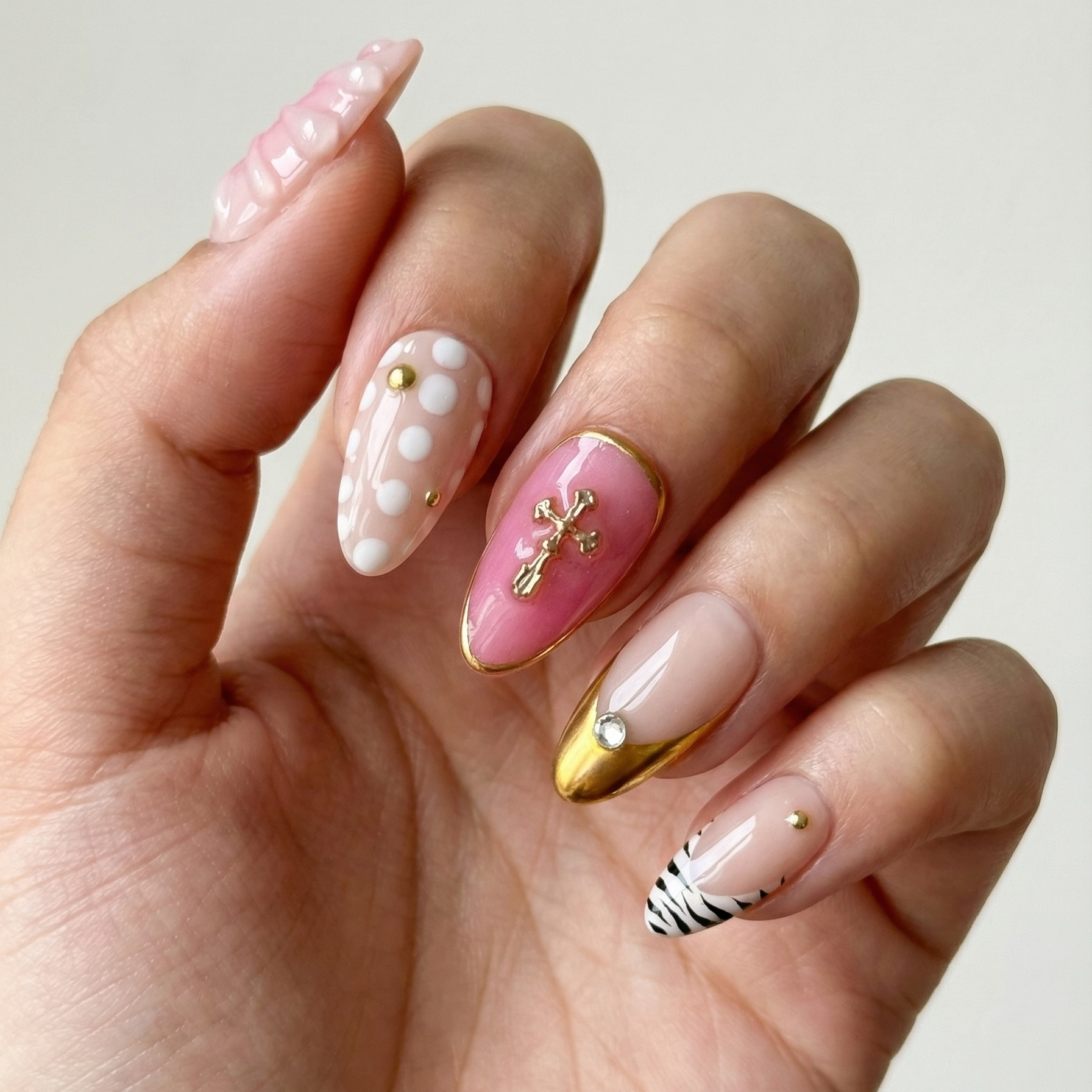 Hand with intricately designed nails featuring various patterns on a plain background