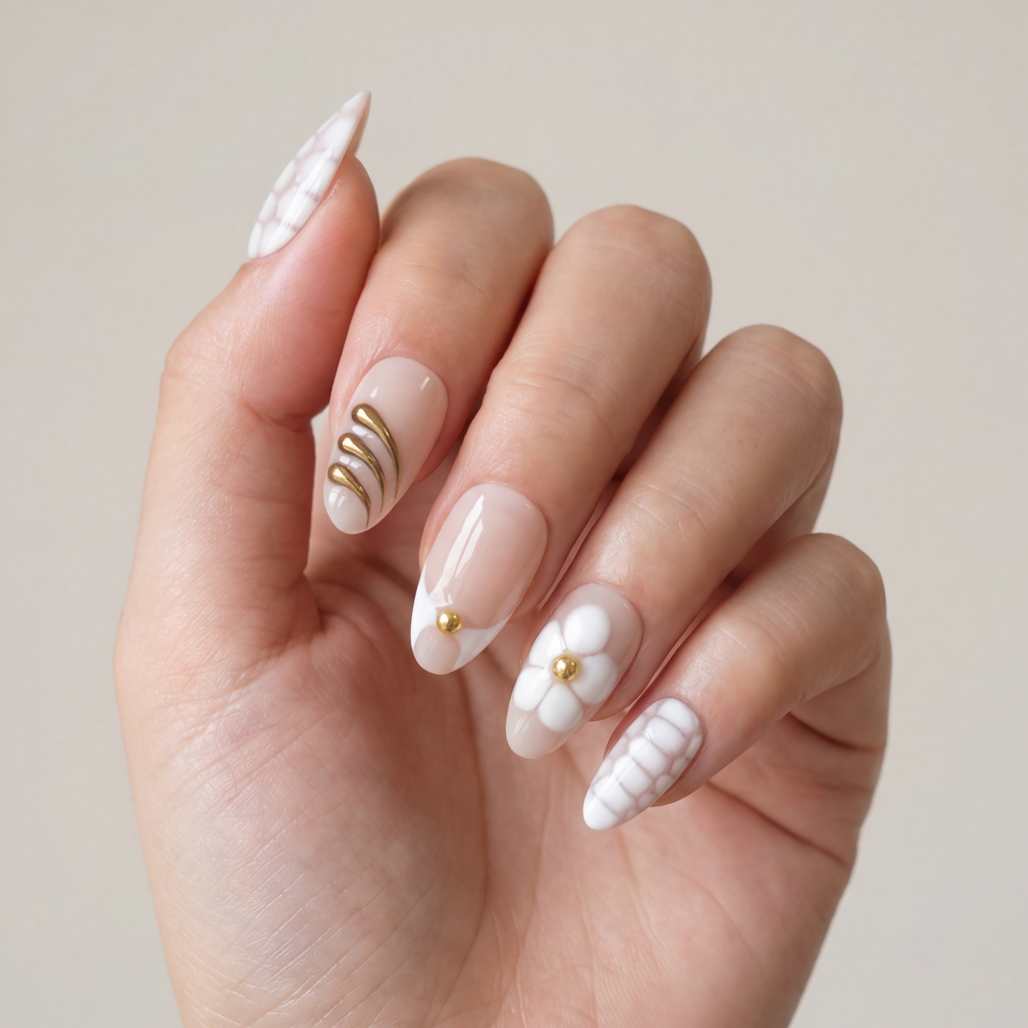 Hand with intricately designed nails featuring floral and gold accents on a neutral background