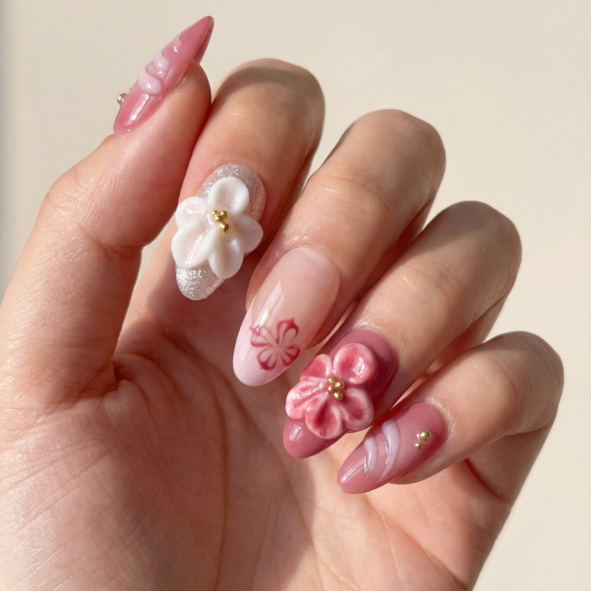 Hand with pink floral nail art on a light background