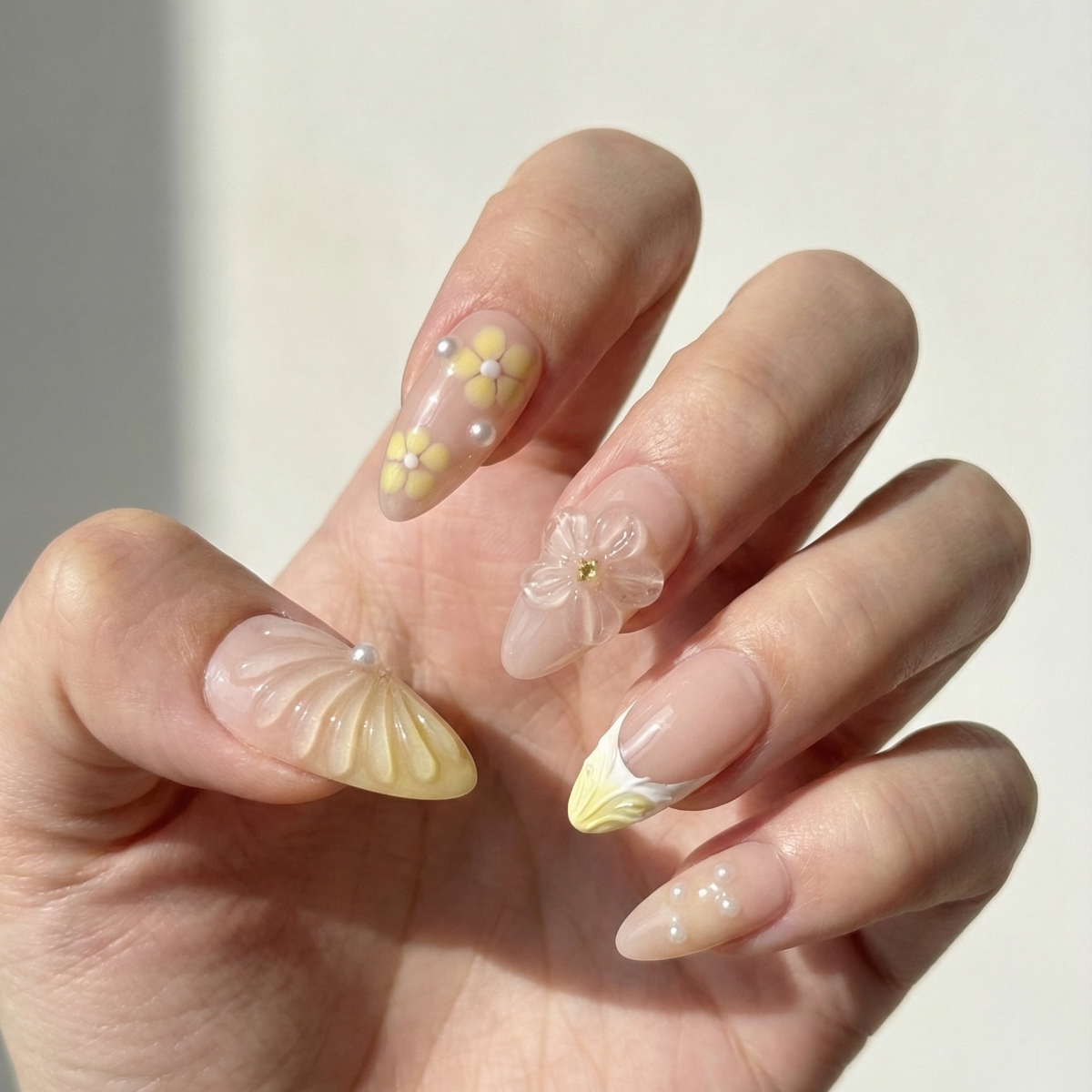 Hand with decorative nails featuring flowers and shells on a plain background